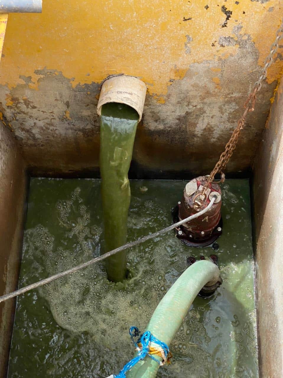 Tuberías de drenaje y agua en pozo de inspección con oxidación y accesorios de conexión