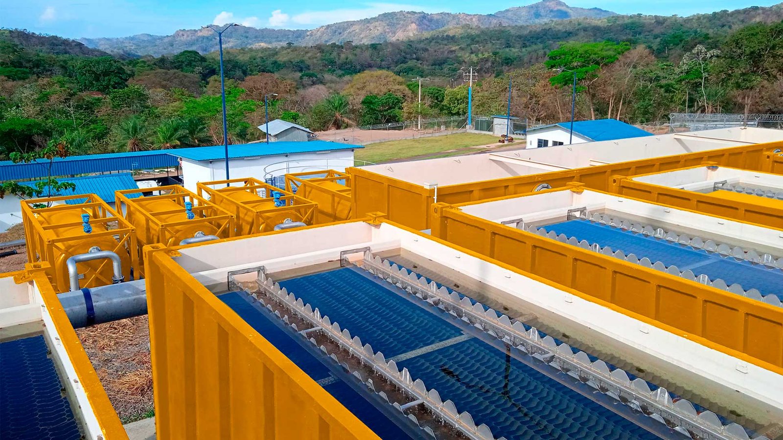 Planta de tratamiento de agua residual con tanques de sedimentación y aireación rodeada de vegetación en zona tropical
