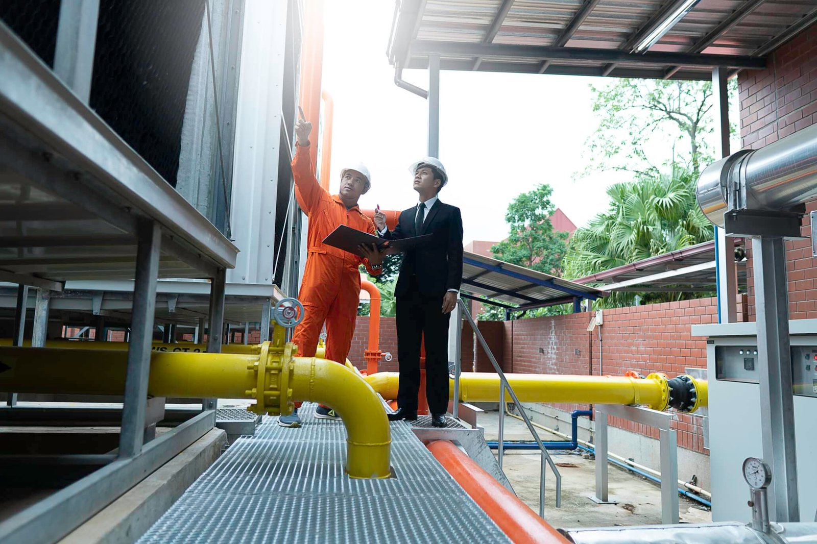 Ingenieros y personal de negocios inspeccionando sistema de tuberías de agua amarillas en planta de tratamiento